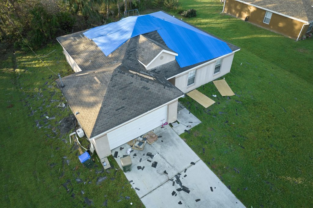 A house with a tarp, as seen in a blog about how to temporarily patch a roof